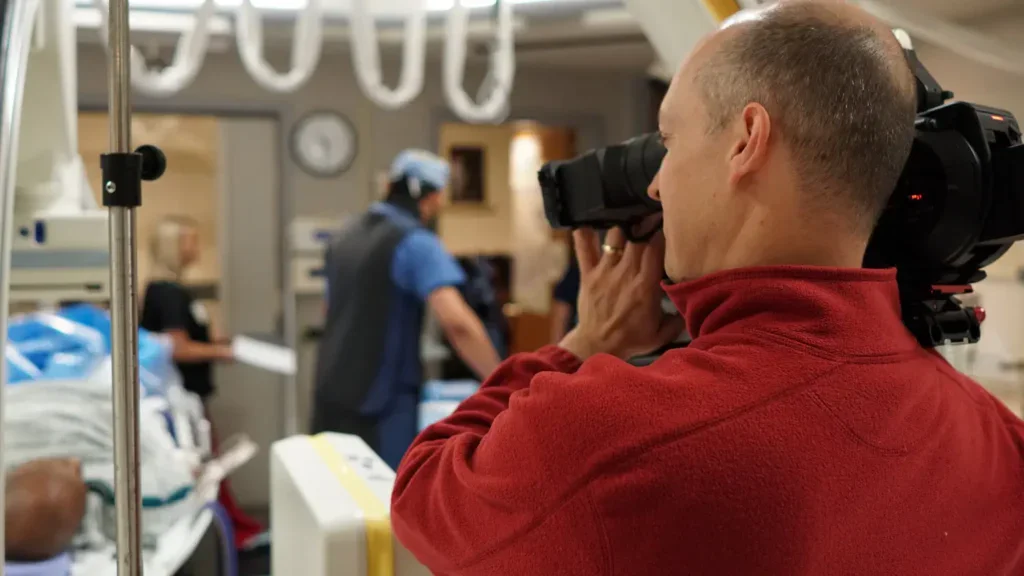 camera crew filming man in hospital bed