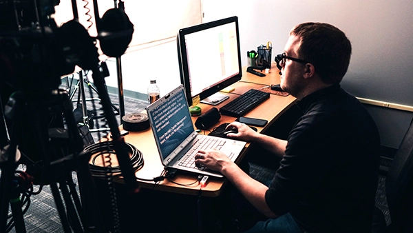 Man at a laptop with teleprompter text